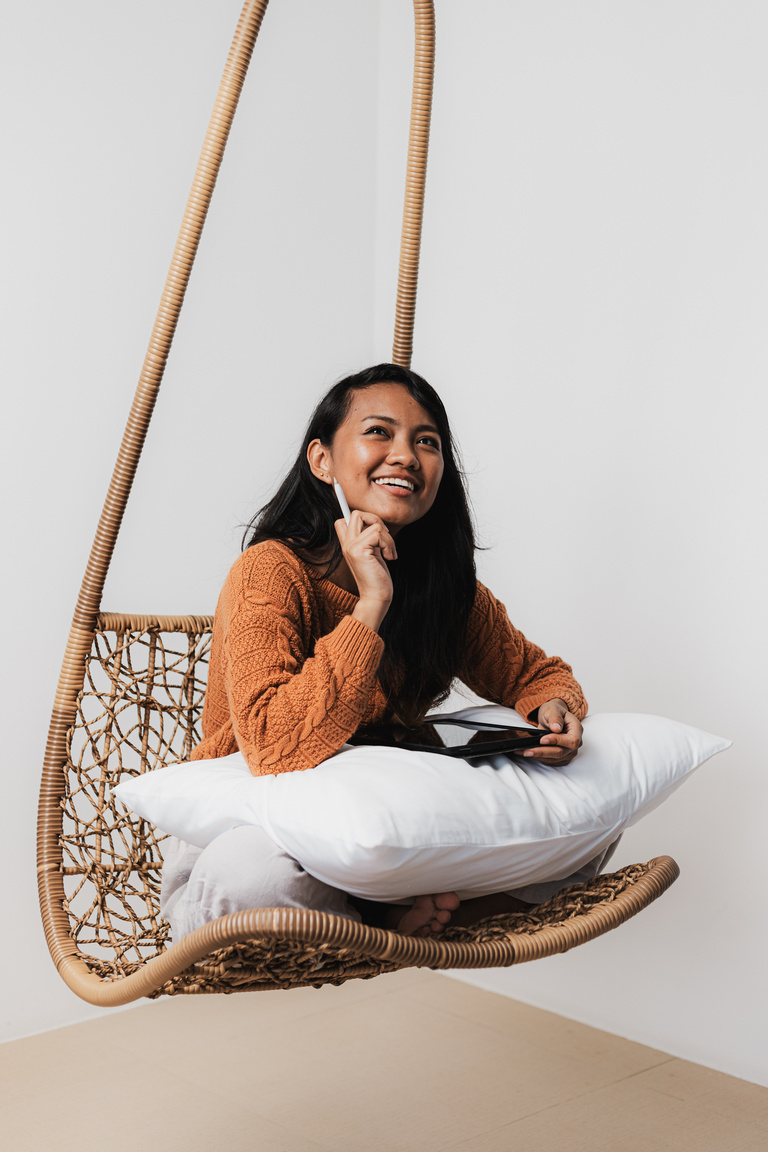 Happy Young Woman Using Tablet Computer on a Hanging Chair